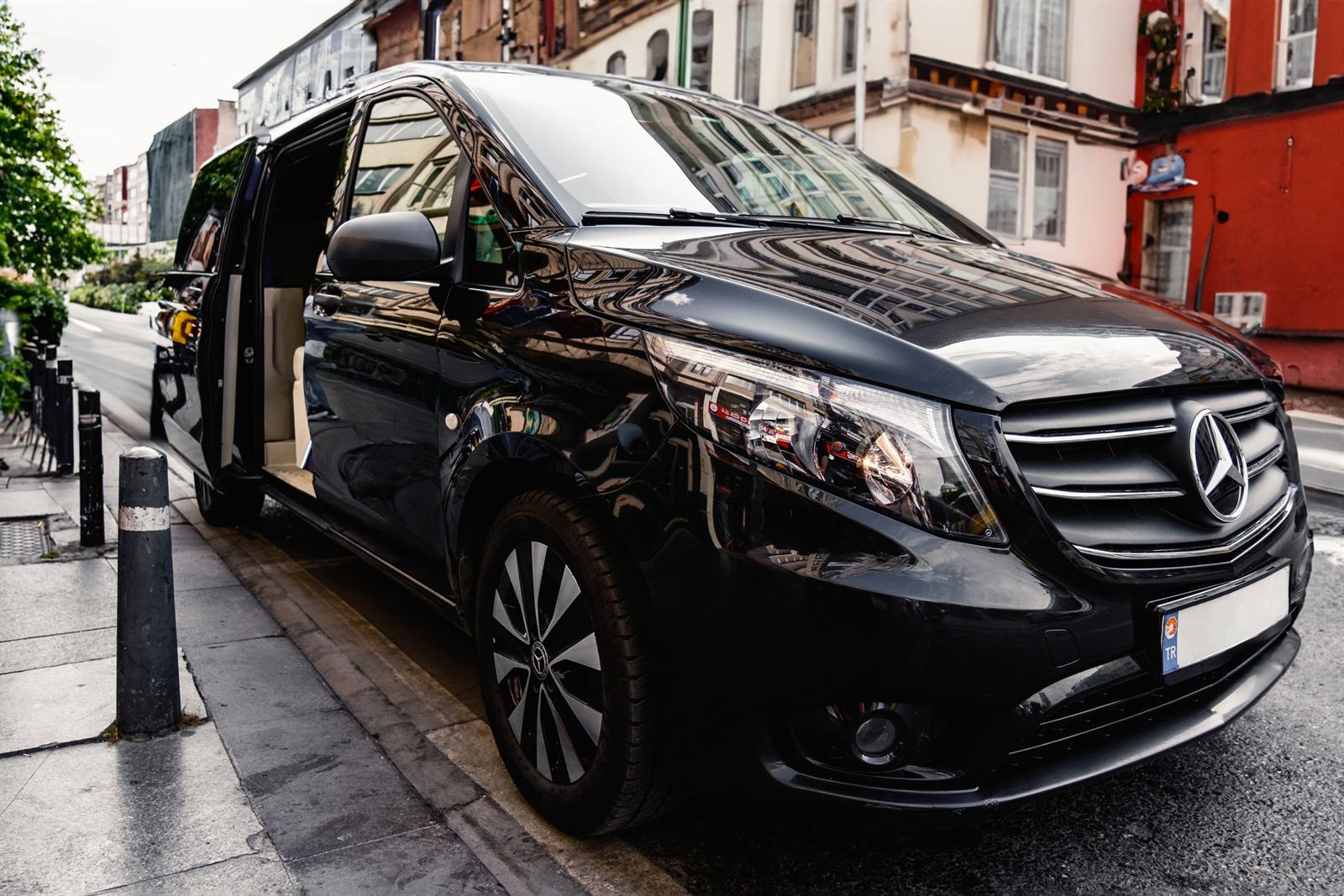 A black van, its sliding door open on a light leather interior